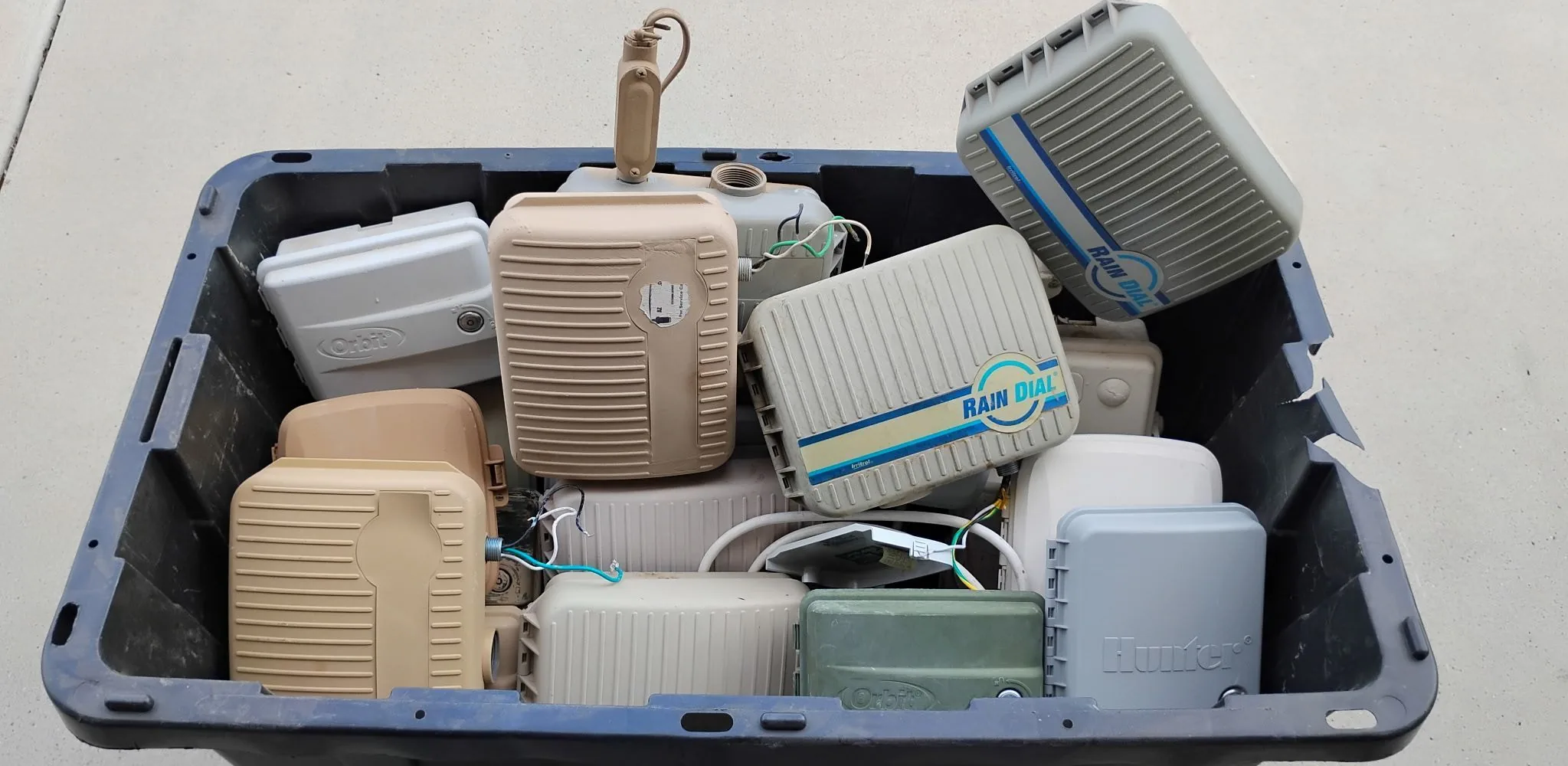 A bin filled with old irrigation clocks removed from Surprise yards, including Orbit and Rain Dial units.
