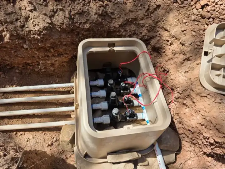 Open irrigation valve box with several valves and red control wires