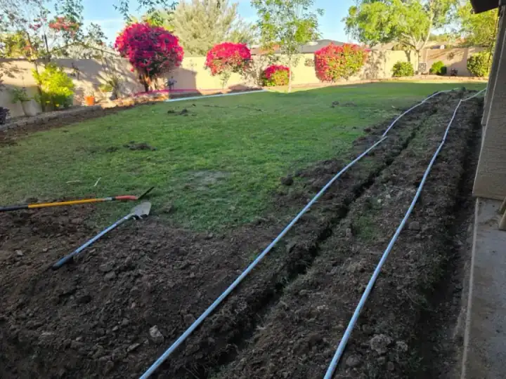 Irrigation lines laid across a lawn and along a freshly dug edge